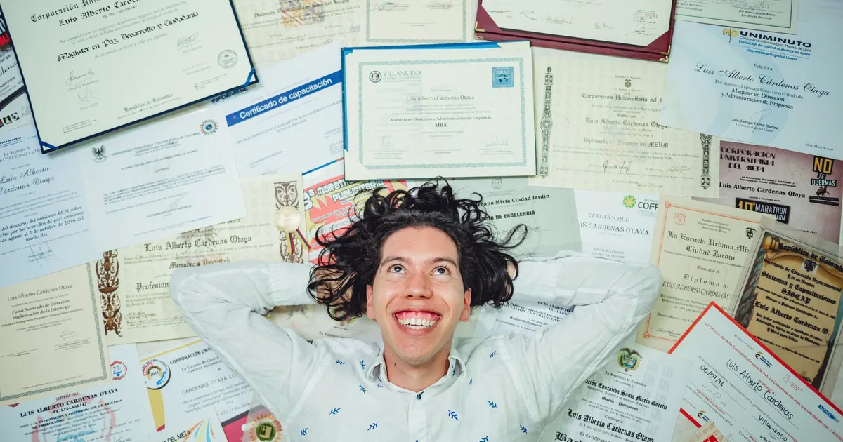 Happy man lying among numerous certificates and diplomas celebrating achievements.
