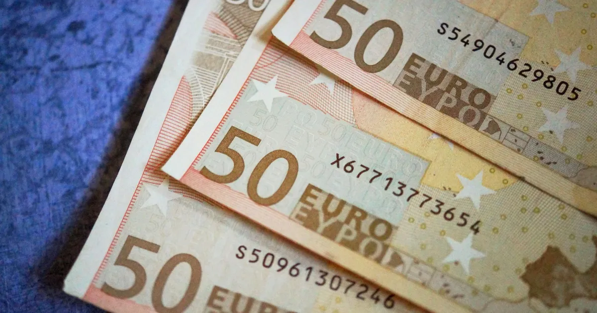 Stack of 50 Euro notes arranged on a textured surface, emphasizing European currency.