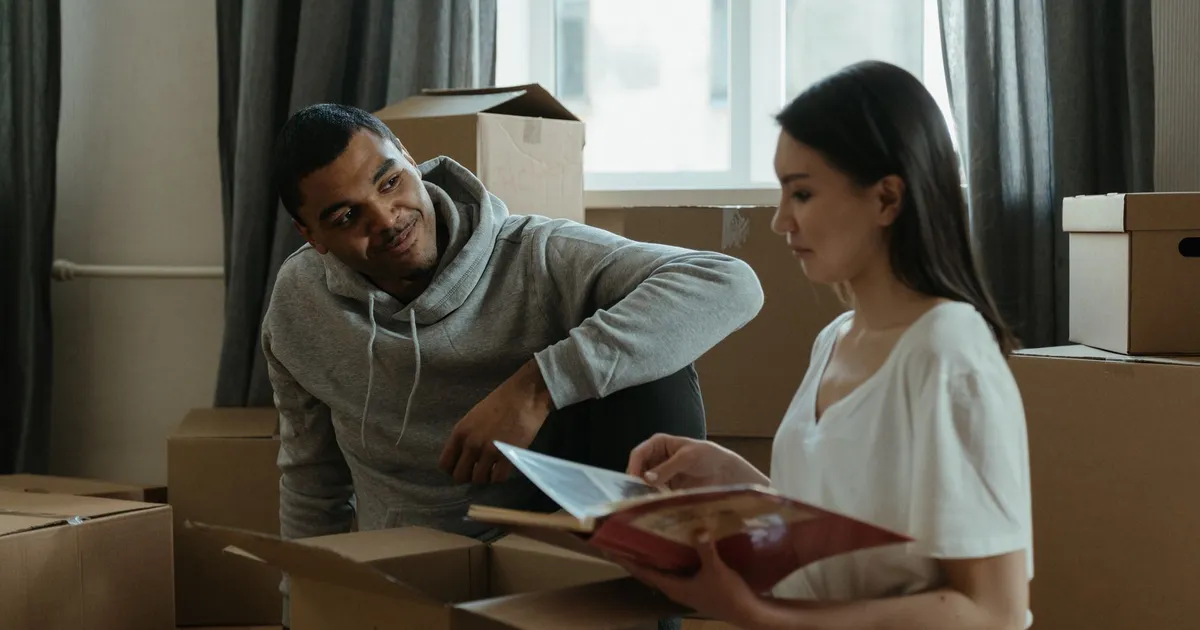 A couple exploring their new home while unpacking boxes and looking at a photo album.