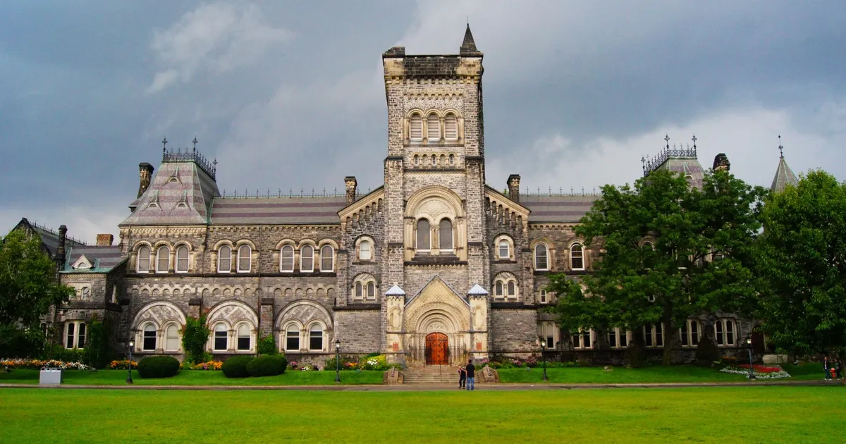 Stunning Gothic Revival building amidst lush greenery under a cloudy sky in Toronto.