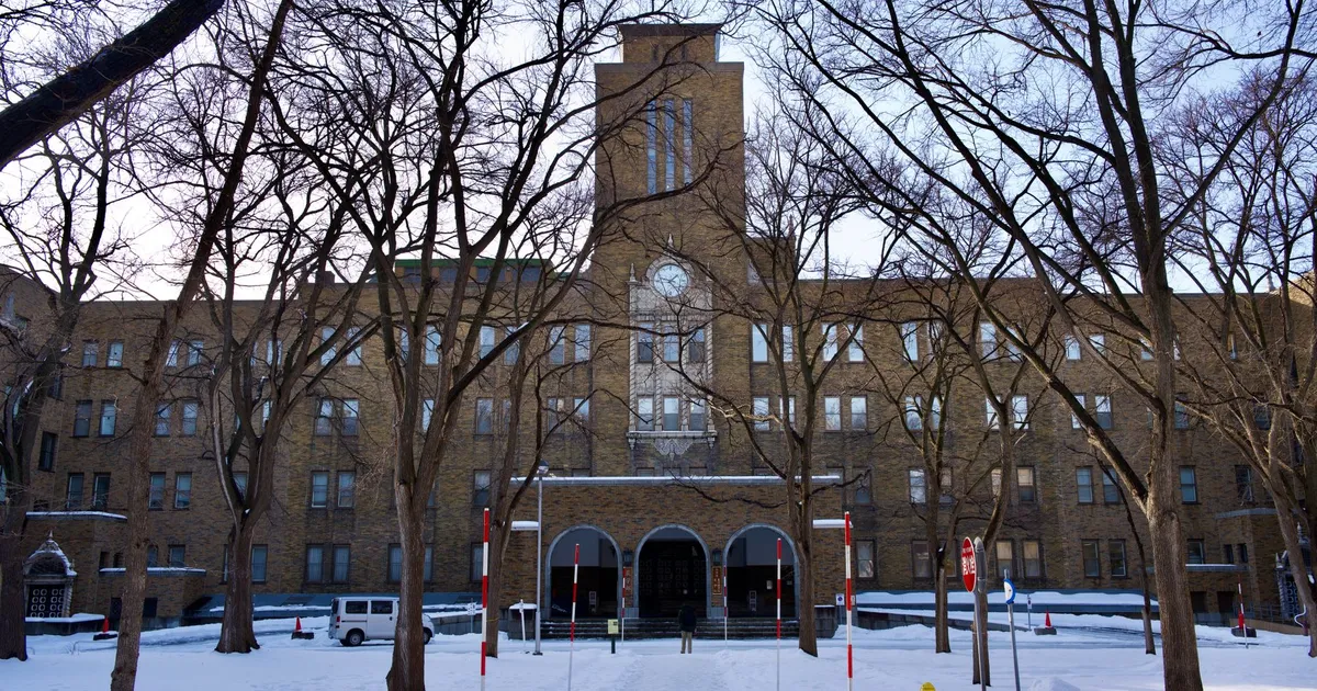 Majestic brick building framed by leafless trees under a clear winter sky.