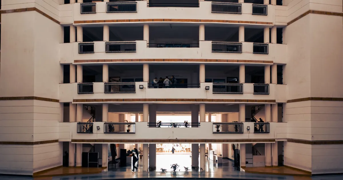 Wide view of a modern university building in Dehradun, India, highlighting architectural design and stairs.