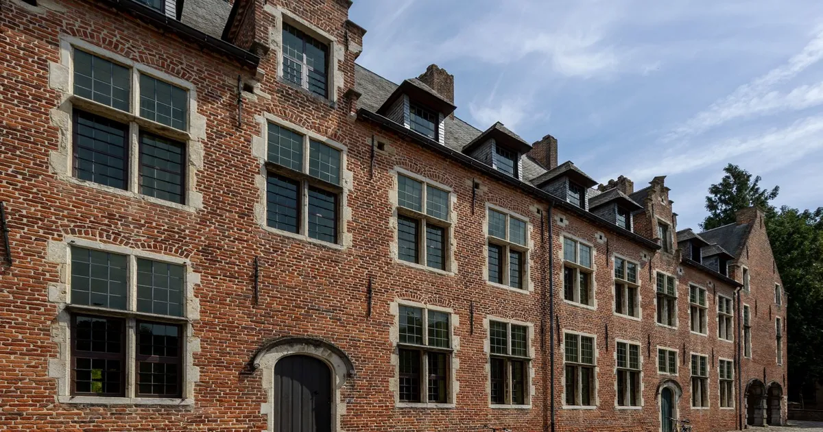 Charming medieval architecture of Groot Begijnhof in Leuven with a clear blue sky backdrop.