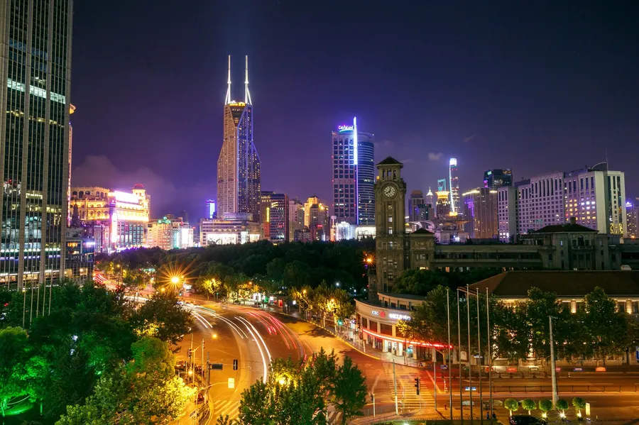 A mesmerizing cityscape at night featuring illuminated skyscrapers and busy street light trails.