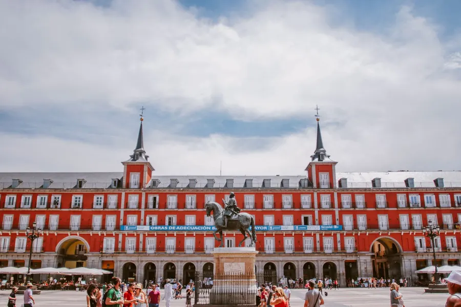 Vibrant view of Plaza Mayor in Madrid with historical architecture and bustling tourists.