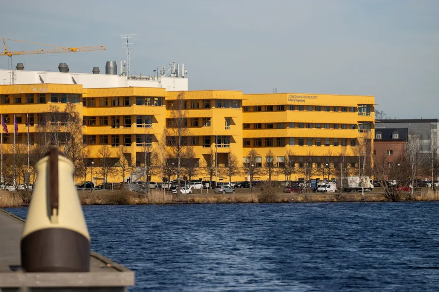 Yellow buildings of Jönköping University School of Engineering in Sweden by the lake.