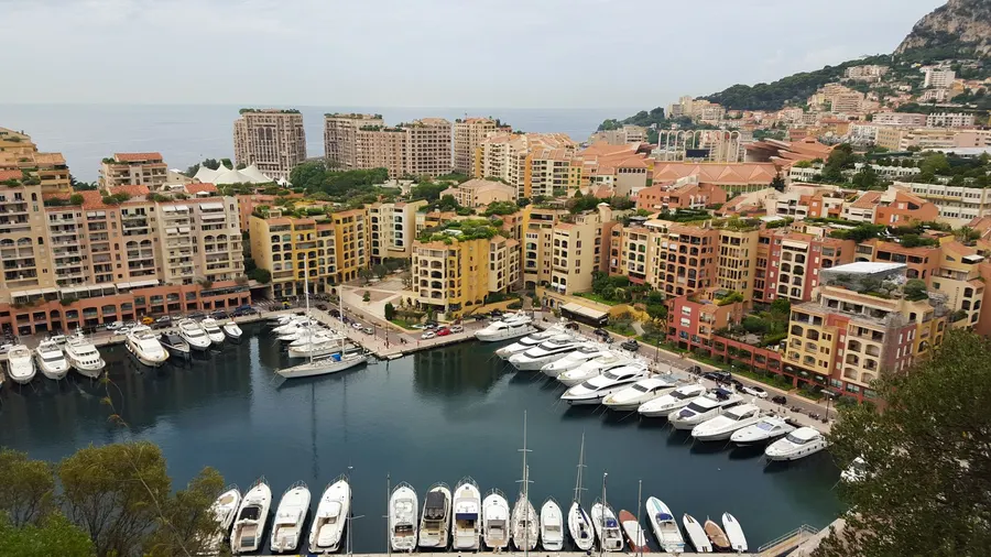 High-angle view of Monaco's marina featuring luxury yachts and colorful buildings against the seaside.