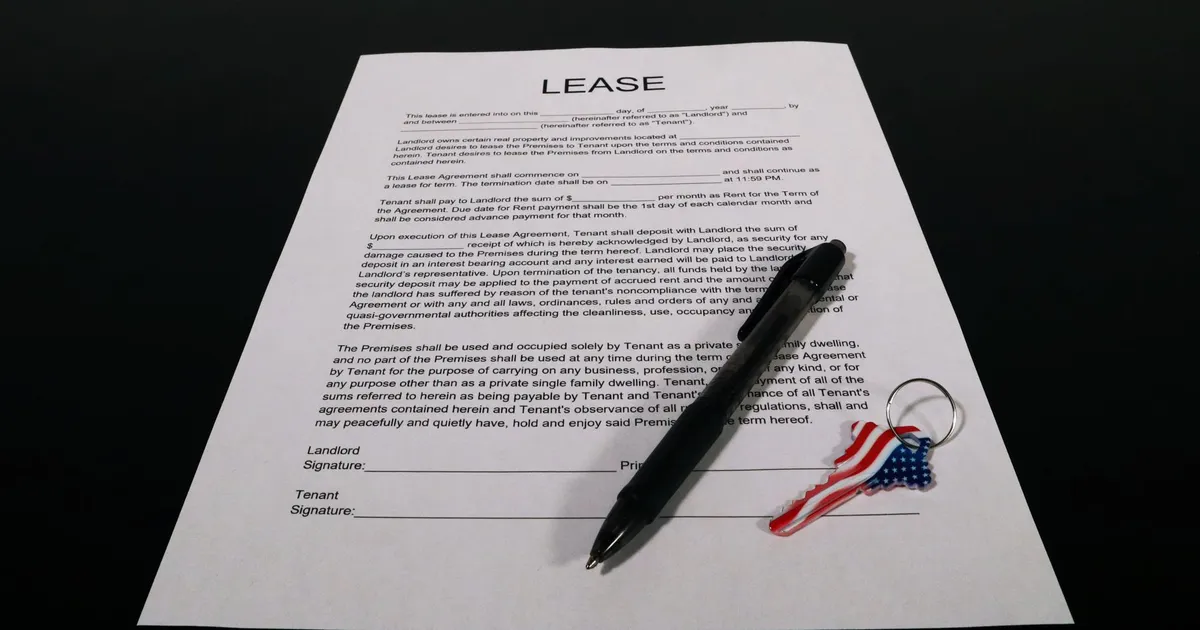 Lease agreement document with pen and American flag keychain on a black table.