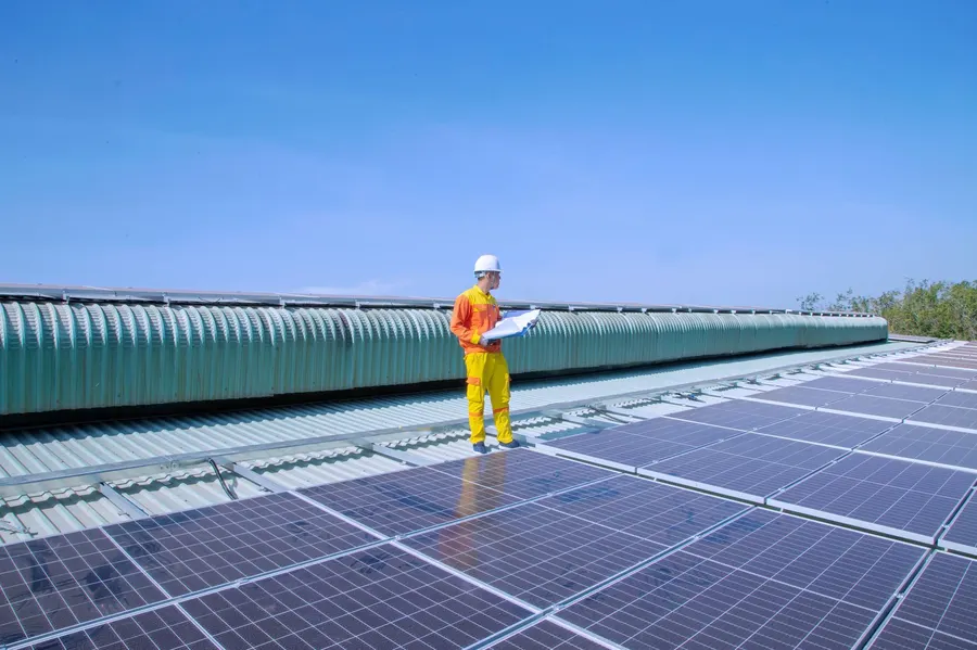 Technician examining solar panels on a rooftop, emphasizing renewable energy.