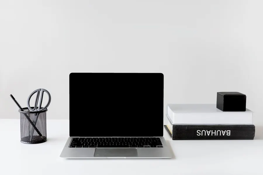 Clean and organized workspace featuring a laptop, books, and pen holder.
