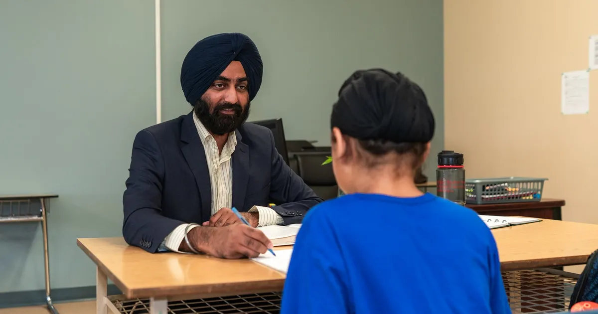 A teacher and student engaging in a one-on-one discussion in a classroom setting.