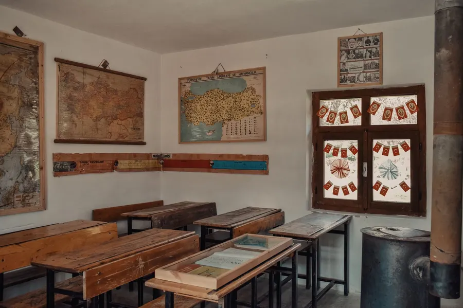 Vintage classroom setting featuring old wooden desks, maps, and Turkish flags.